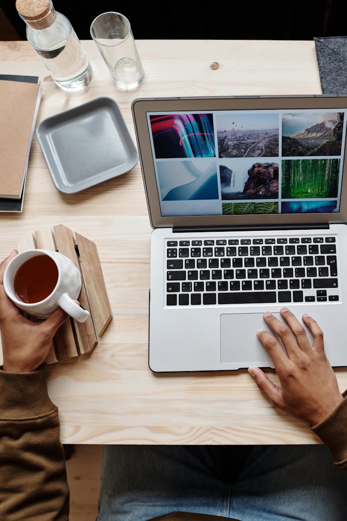 Overhead view of a person working remotely with a laptop and coffee on a wooden table.
